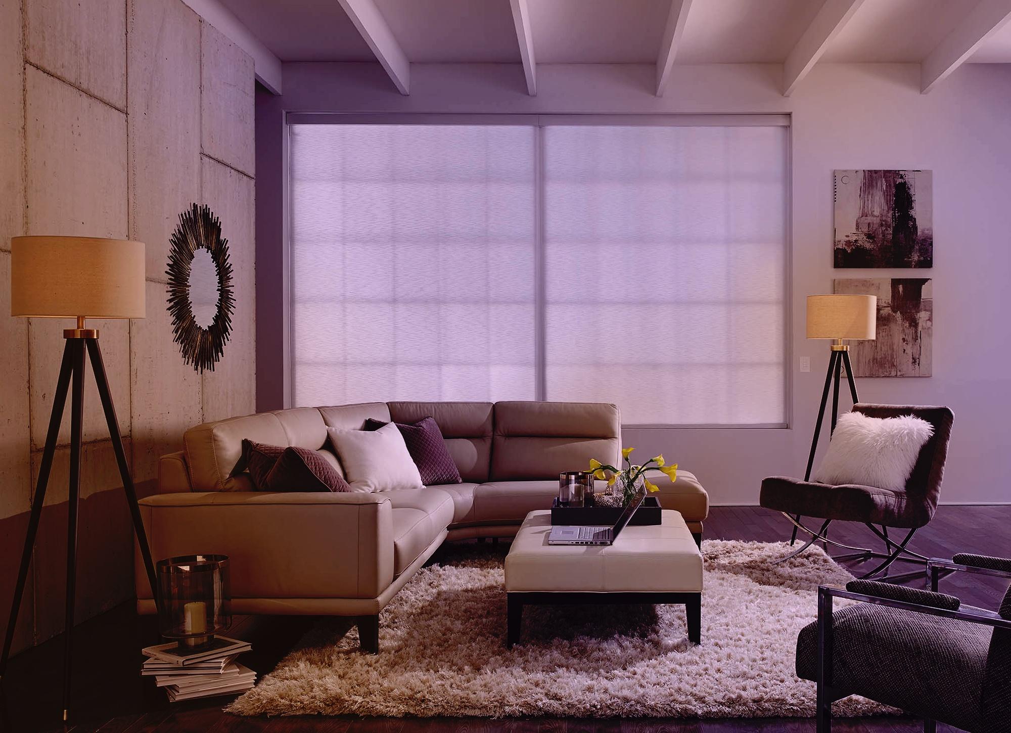 Warmly lit living room featuring a white sectional sofa, floor lamps, and a welcoming ambiance for social gatherings.