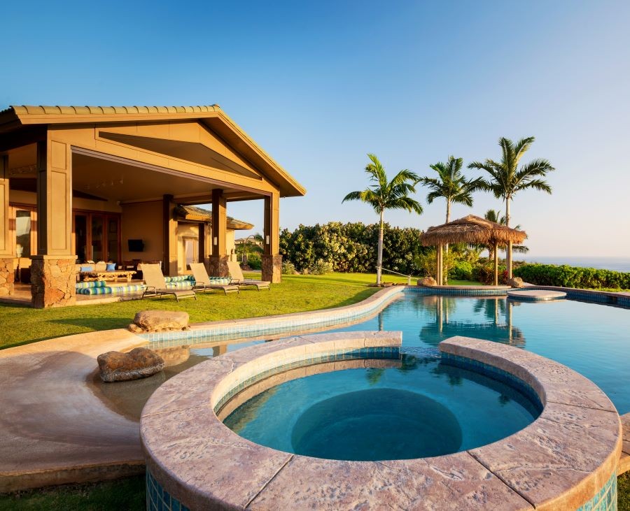 A backyard with a pool, hot tub, and small tiki hut.