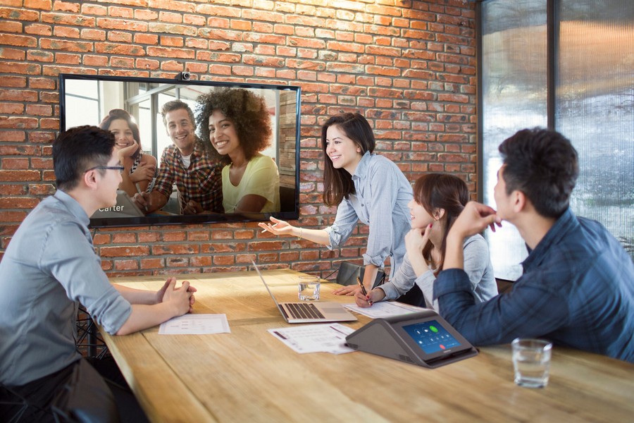 People sitting in a conference room having a meeting on a video call.