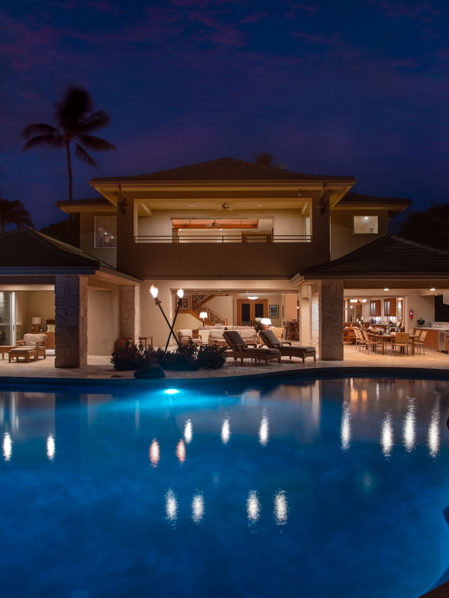 Luxury home exterior with illuminated pool and open patio area at night