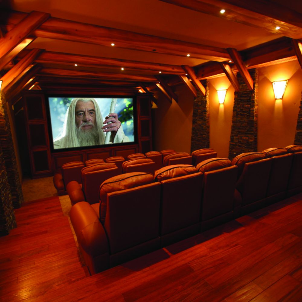 Cozy home theater with leather recliners, wood accents, and movie playing on large screen