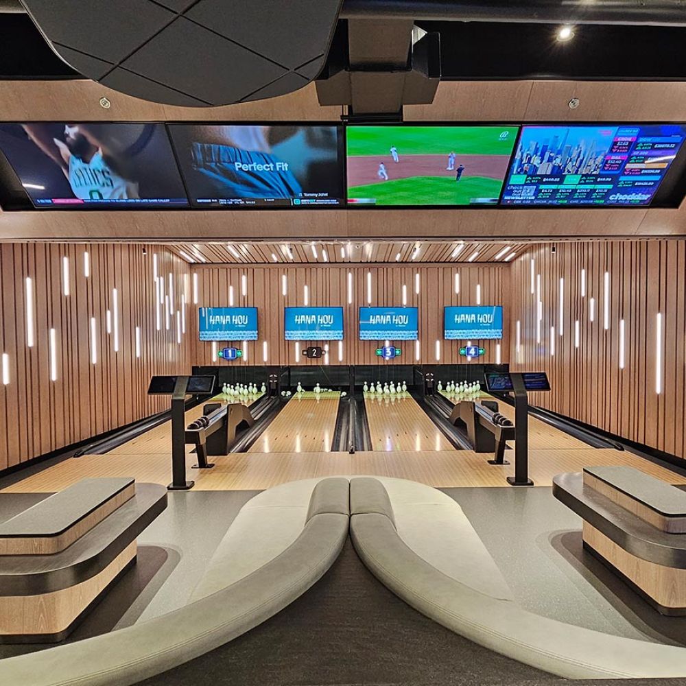 Luxury bowling alley with multiple lanes, digital score screens, and lounge seating