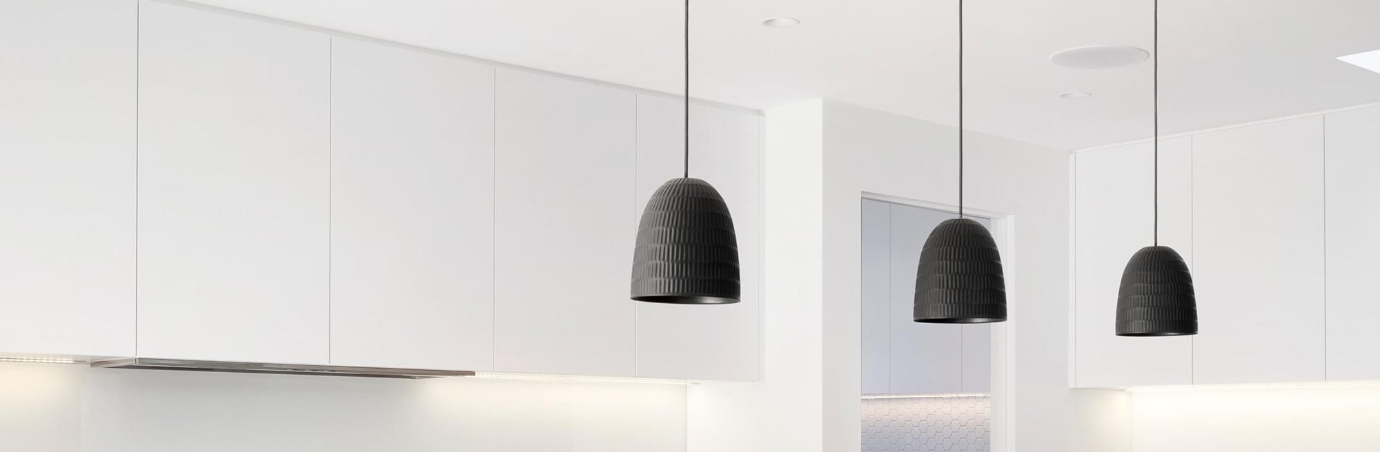 Minimalist kitchen with black pendant lights hanging over a white island.