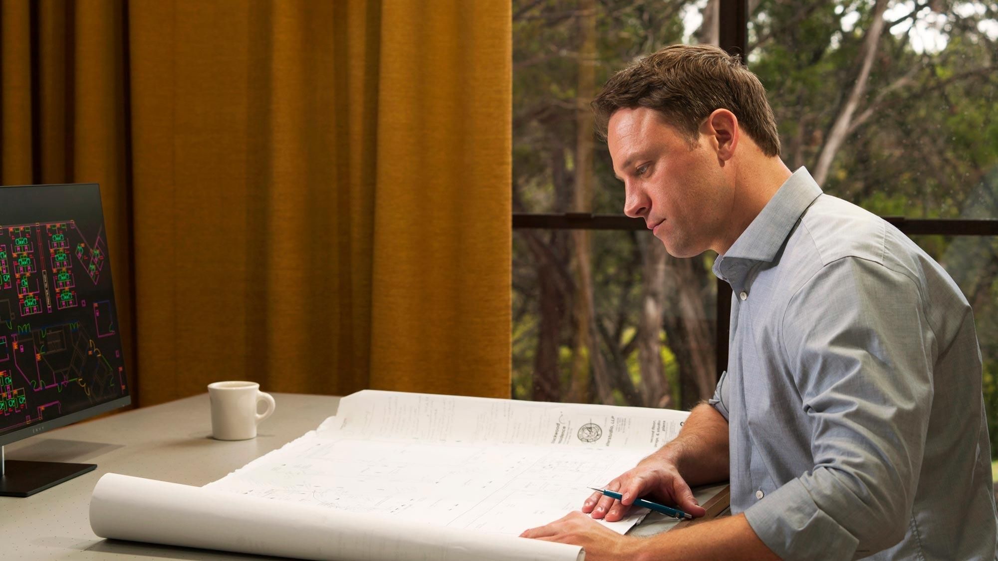 Man reviewing blueprints at his desk, illuminated by Ketra lighting, ensuring clear visibility and focus.